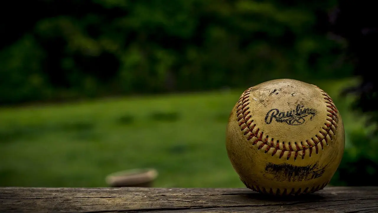 Beat up baseball on the wooden railing 