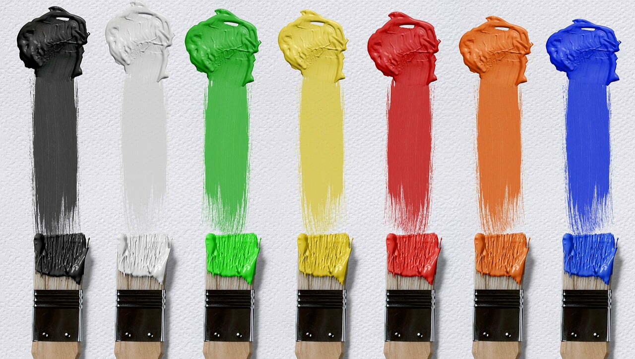 Paint brushes with different colours painted on a canvas