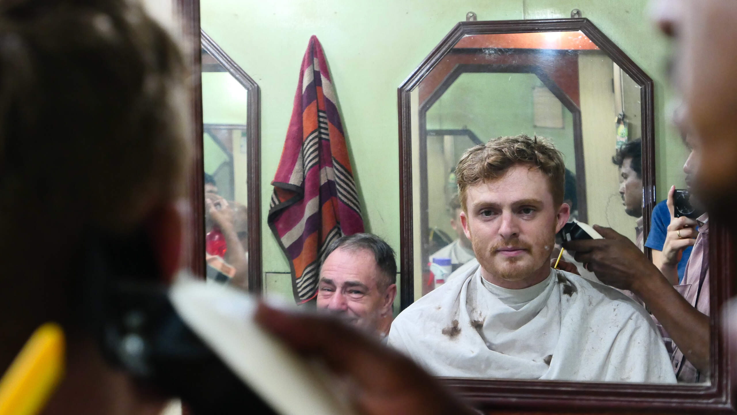 Nomadic Samuel getting a haircut and shave at a barbershop in Kolkata, India