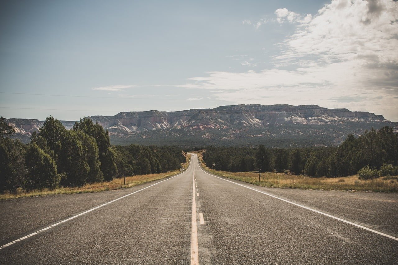 Long country road in the countryside with mountain backdrop