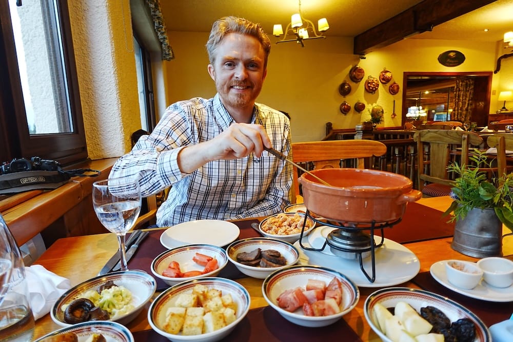 Samuel Jeffery Dining on Traditional Fondue at Llao Llao Hotel in Bariloche, Río Negro, Patagonia, Argentina Samuel Jeffery stirs a traditional Alpine-style cheese fondue at Llao Llao Hotel in Bariloche, Río Negro, Patagonia, Argentina, with bowls of bread, potatoes, meat, fruit and vegetables arranged across the table.